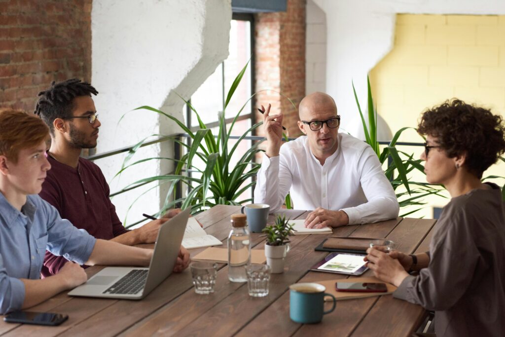 Réunion d'une femme et de trois hommes autour d'une table pour discuter de la différence entre interprétation simultanée et interprétation consécutive