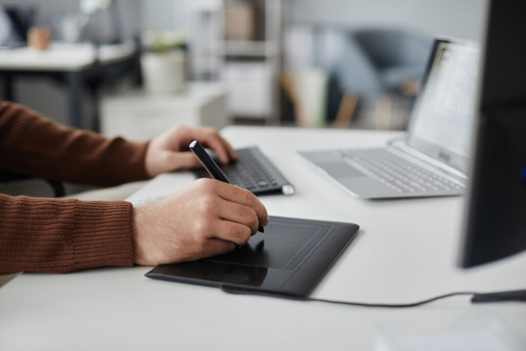 Mains d'un homme realisant une transcription ou un sous-titrage en utilisant une tablette et un ordianteur