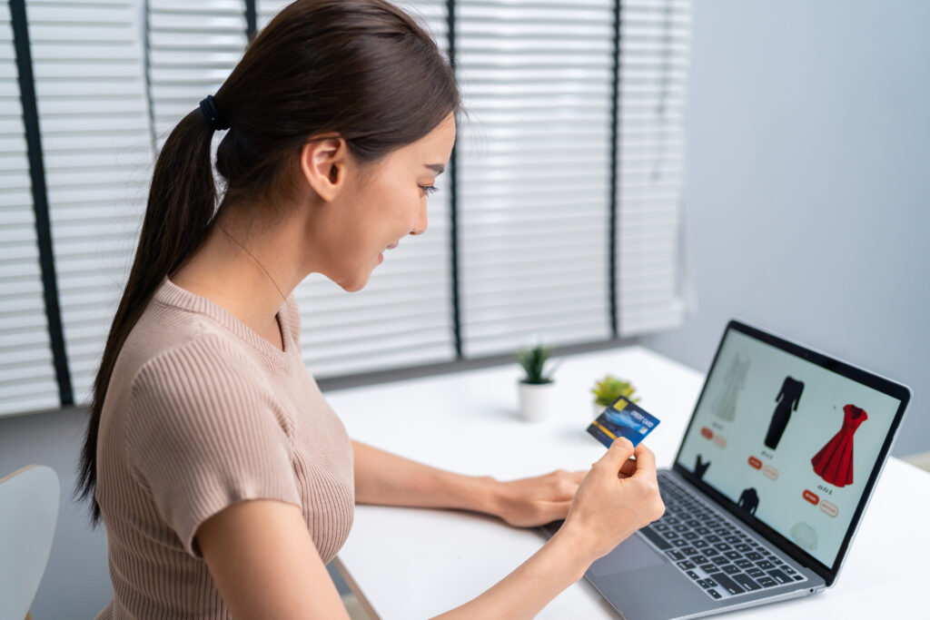 Jeune femme devant son ordinateur, faisant du shopping en ligne sur un site e-commerce
