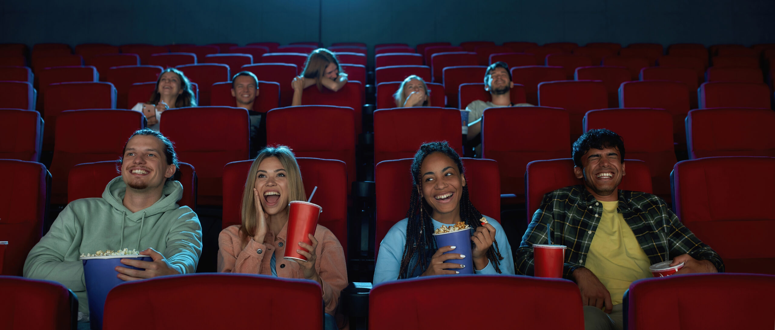 Un groupe d'amis heureux et divers rient en regardant ensemble le film et en lisant les sous-titres tratuire l'humour et les jeux de mots, assis dans l'auditorium du cinéma