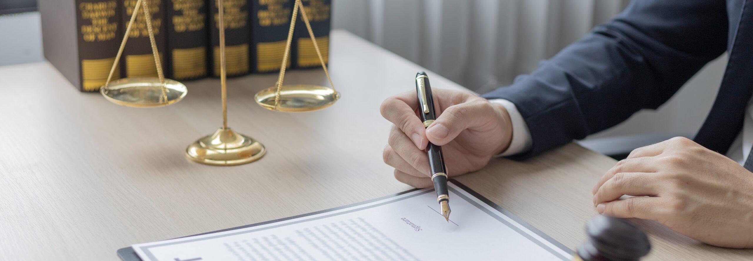 mains d'un homme en costume en train de signer un document juridique