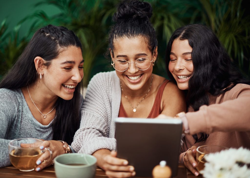 Trois touristes joyeuses consultent la carte d'un restaurant
